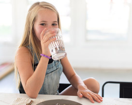 Young girl drinking a glass of water.